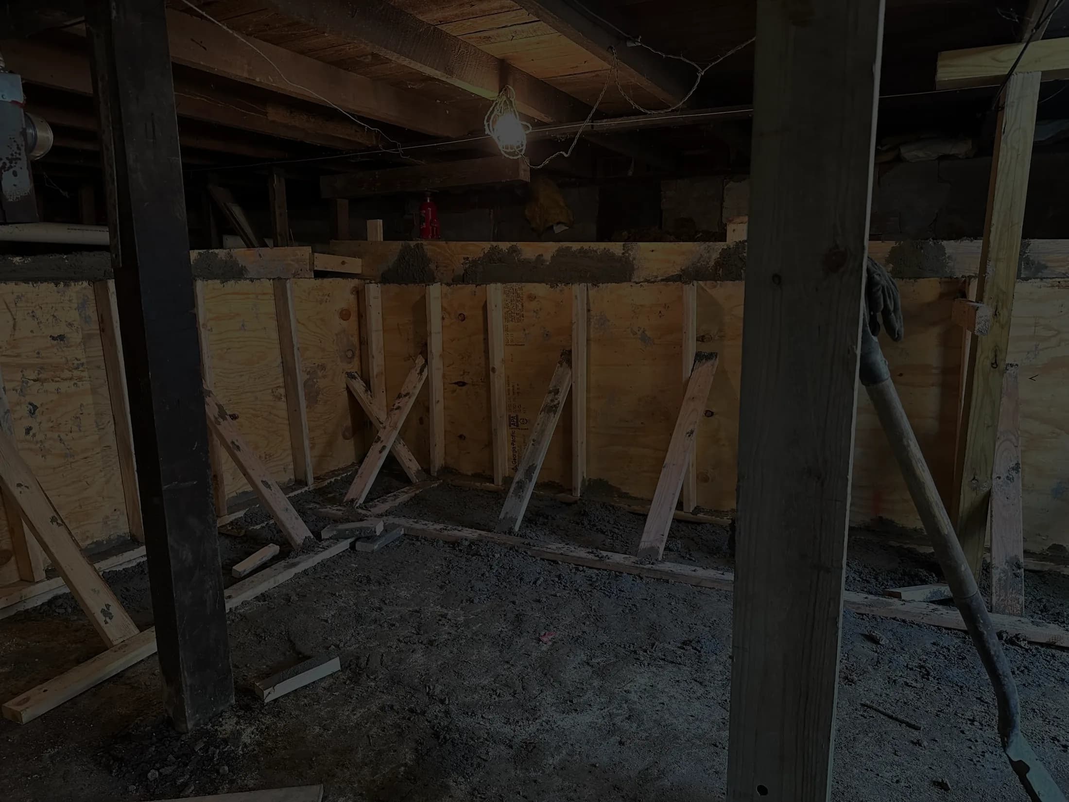 Braced plywood forms and timber shoring against a basement wall during a concrete pour